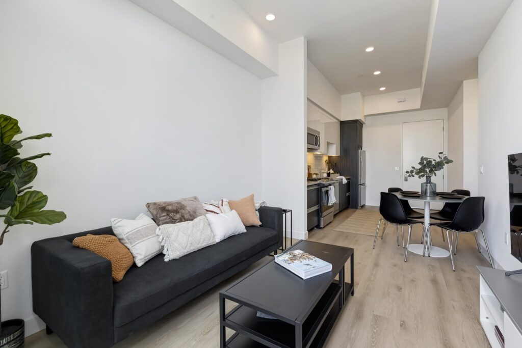 living room view with couch, TV, decor, and view of the kitchen with dining table
