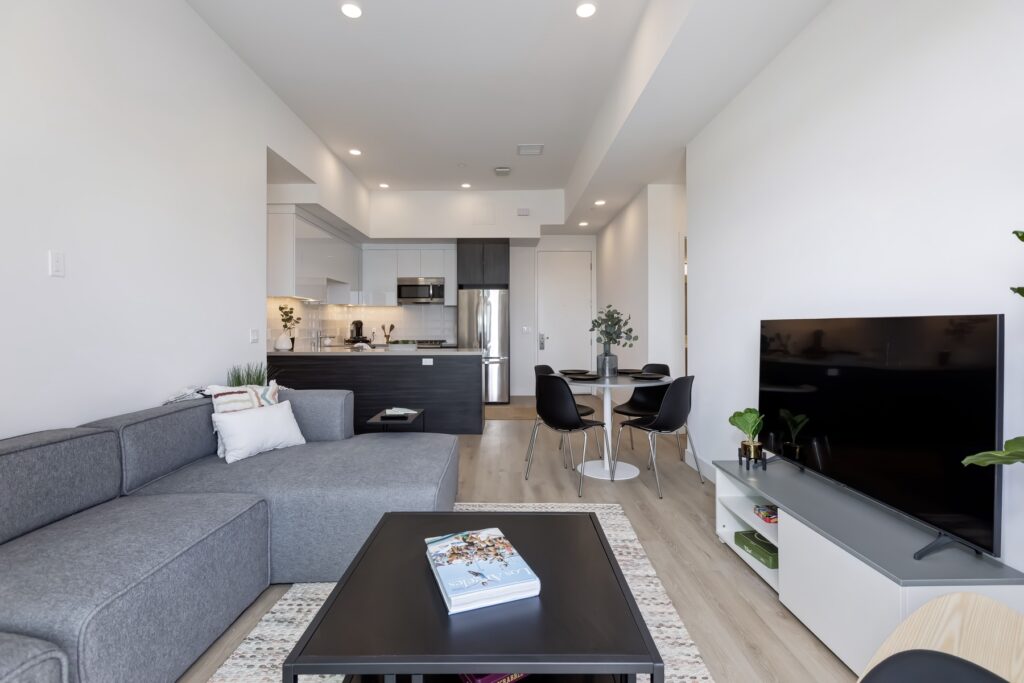 living room view with couch, TV, decor, and view of the kitchen with dining table