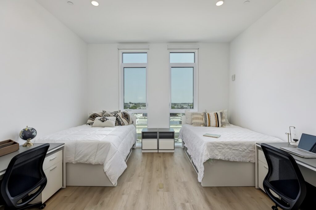 bedroom with two beds, two windows, small desks, and decor