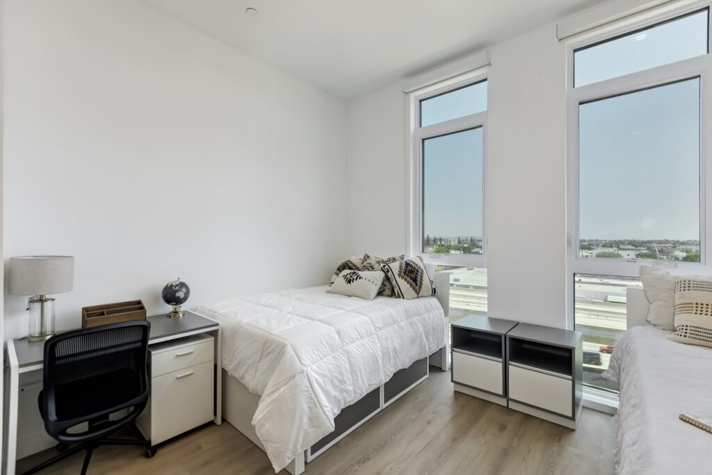 bedroom with two beds, two windows, small desk, and decor