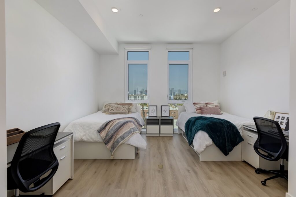 bedroom with two beds, two windows, small desks, and decor