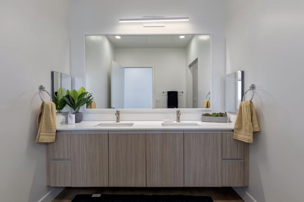 bathroom with dual sinks, dual side mirrors, and large main mirror
