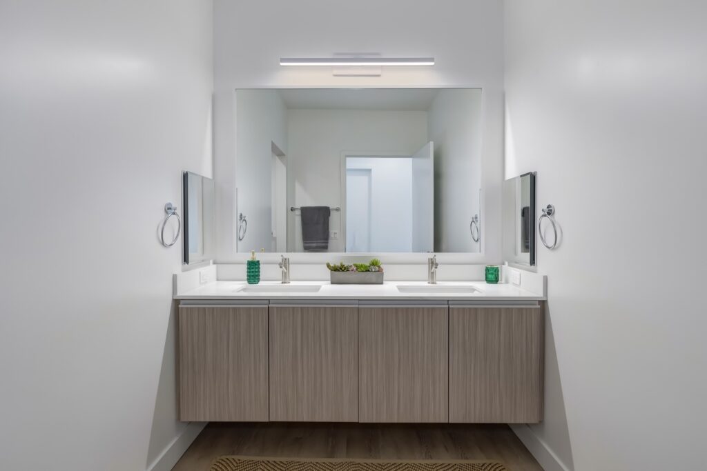 bathroom with dual sinks, dual side mirrors, and large main mirror