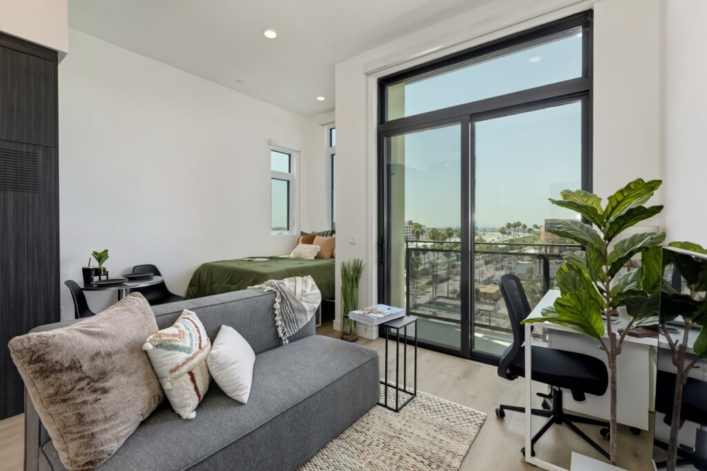 living area with balcony view, small desk, couch, and view of bedroom area