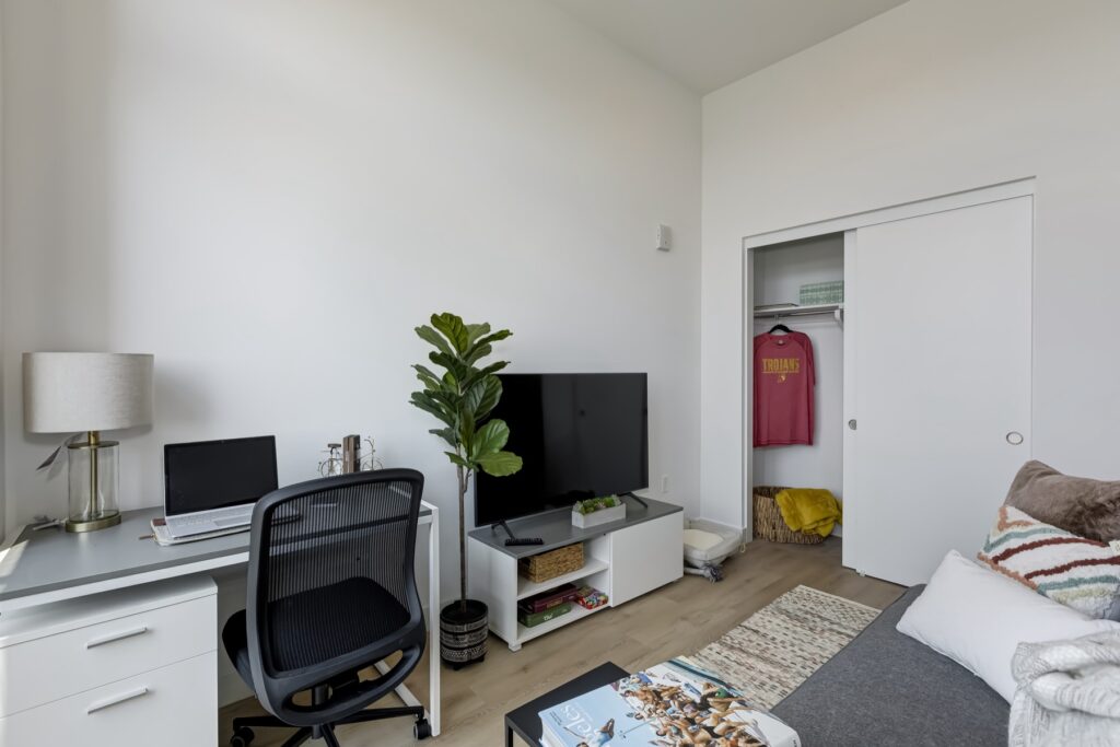 living room area with small desk, sliding closet door, TV, couch, and decor