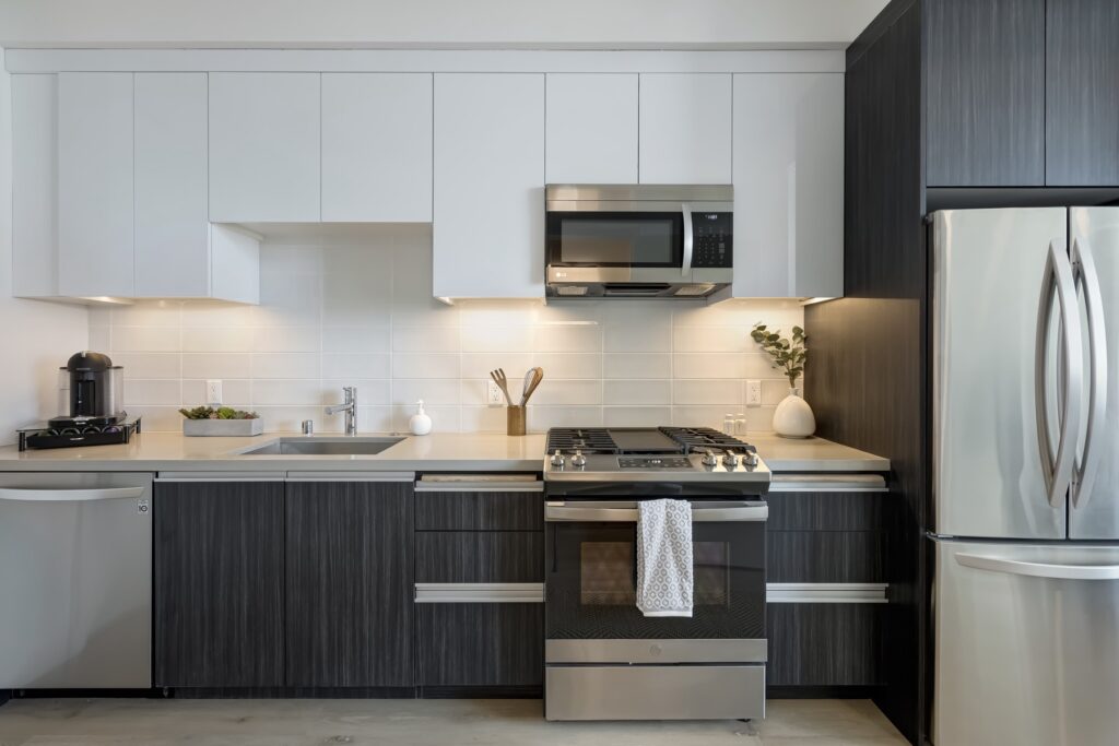 kitchen with under cabinet lighting, stainless steel appliances, and white and black cabinets