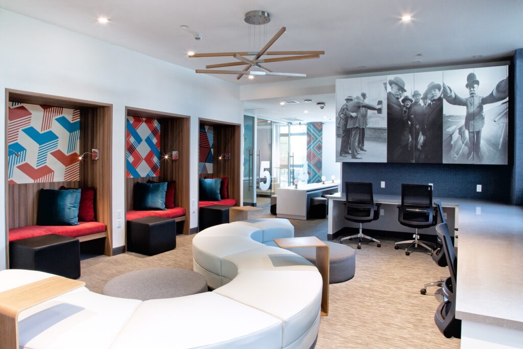 Interior clubhouse with lounge and table seating, computer desks, designer lighting, and carpet flooring