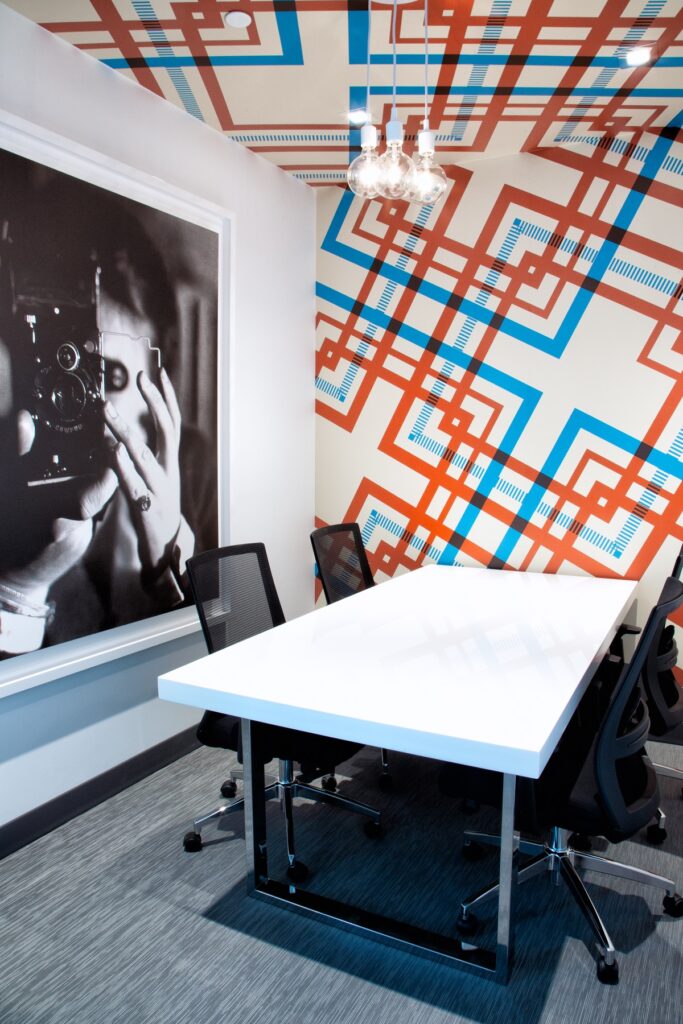 Clubhouse meeting room with chair seating, desk table, accent colored walls, carpet flooring, and designer lighting