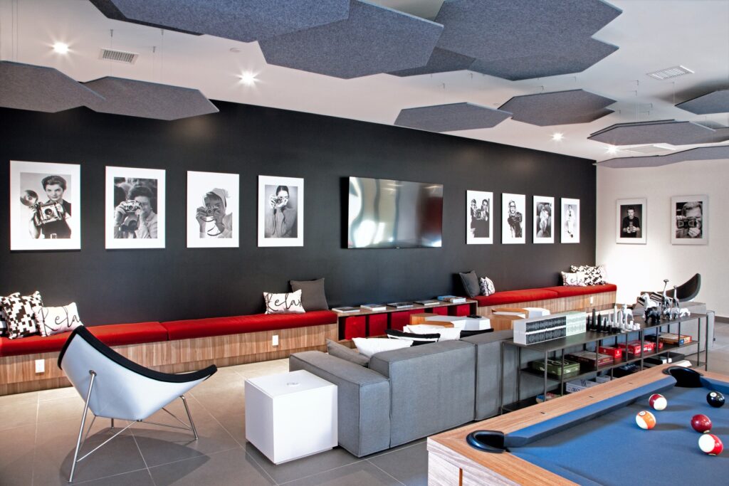 Interior clubhouse lounge with pool table, board games, couch seating, tile flooring, and designer lighting
