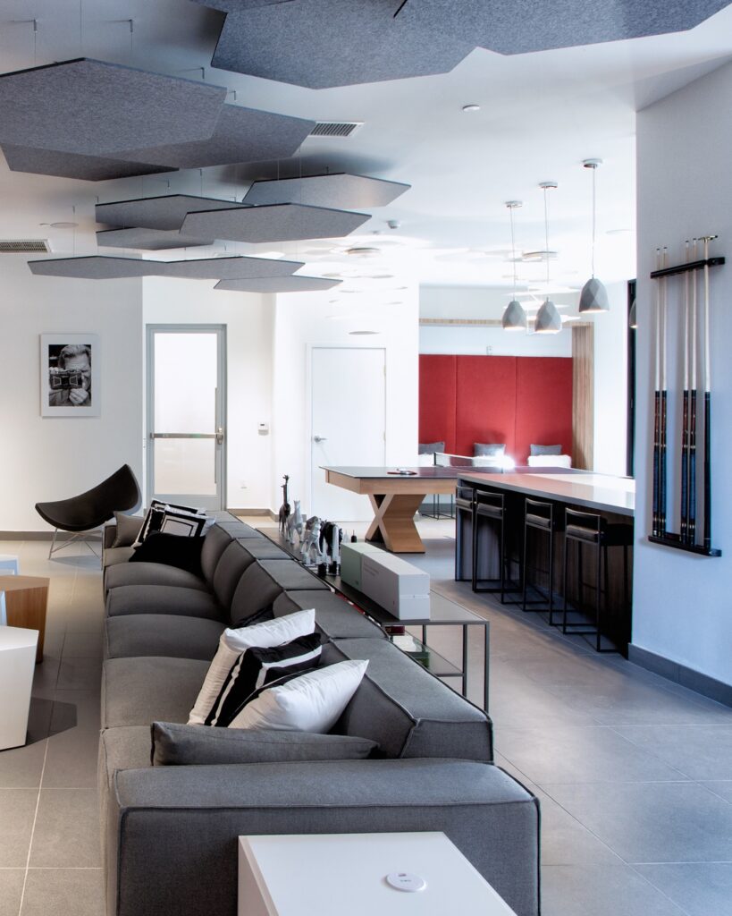 Interior clubhouse lounge with ping pong table, board games, couch seating, tile flooring, and outdoor and designer lighting