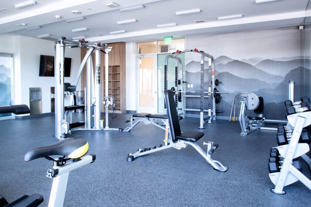 Indoor gym area with weights, weight machines, cardio machines, television, and tile flooring