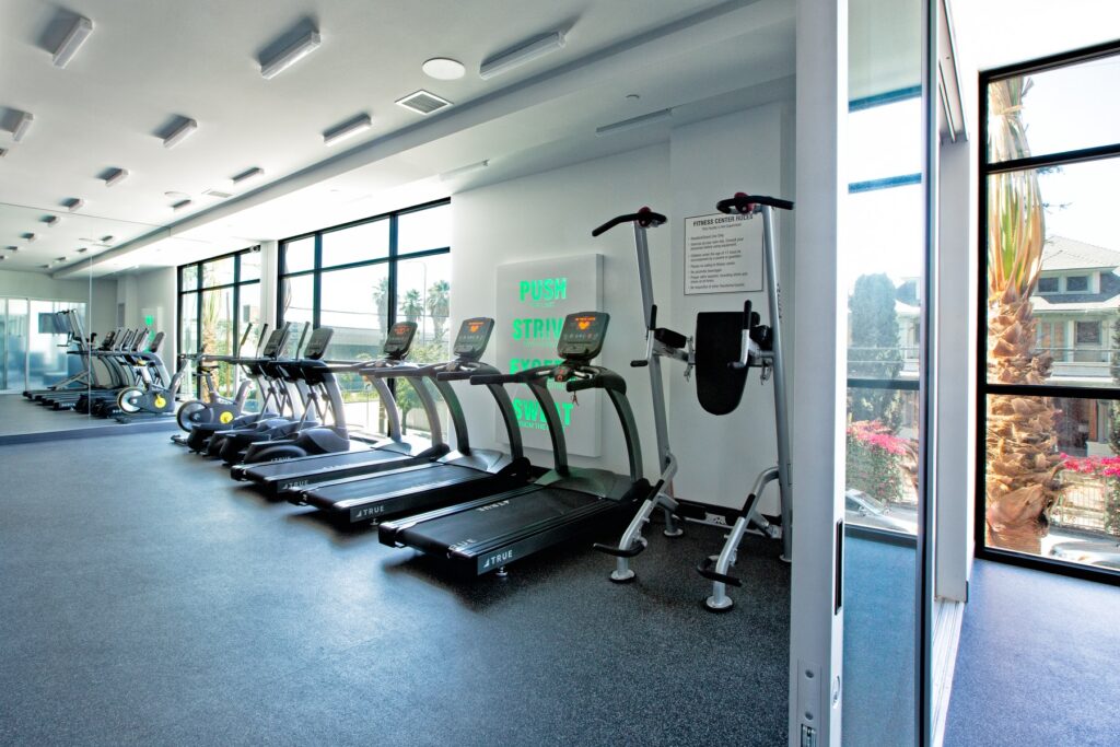 Indoor gym area with cardio machines, mirror, large windows, and tile flooring