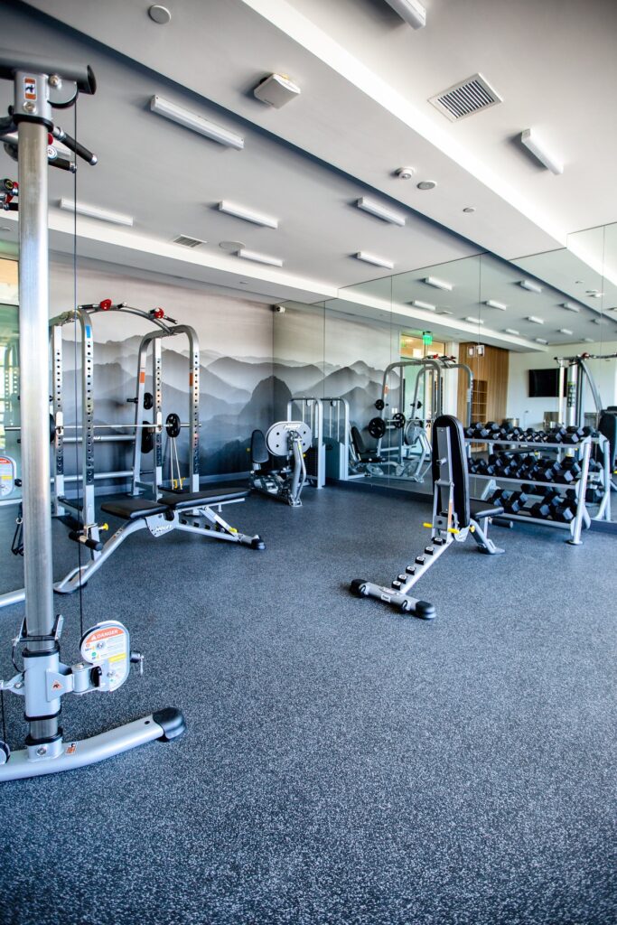Indoor gym area with cardio machines, weight machines, weights, outdoor lighting, and tile flooring