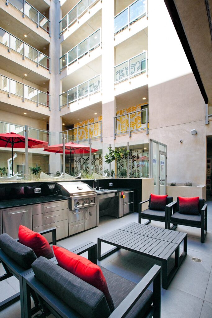 Outdoor courtyard with lounge seating, grilling station, sink, stainless steel appliances, and tile flooring