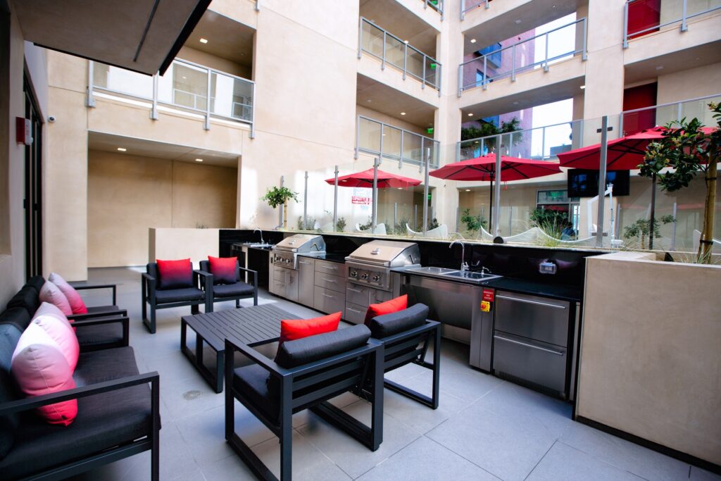 Outdoor courtyard with lounge seating, grilling stations, sinks, stainless steel appliances, and tile flooring