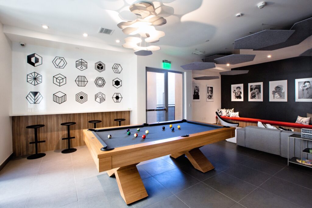 Interior clubhouse lounge area with pool table, couch seating, designer lighting, and tile flooring