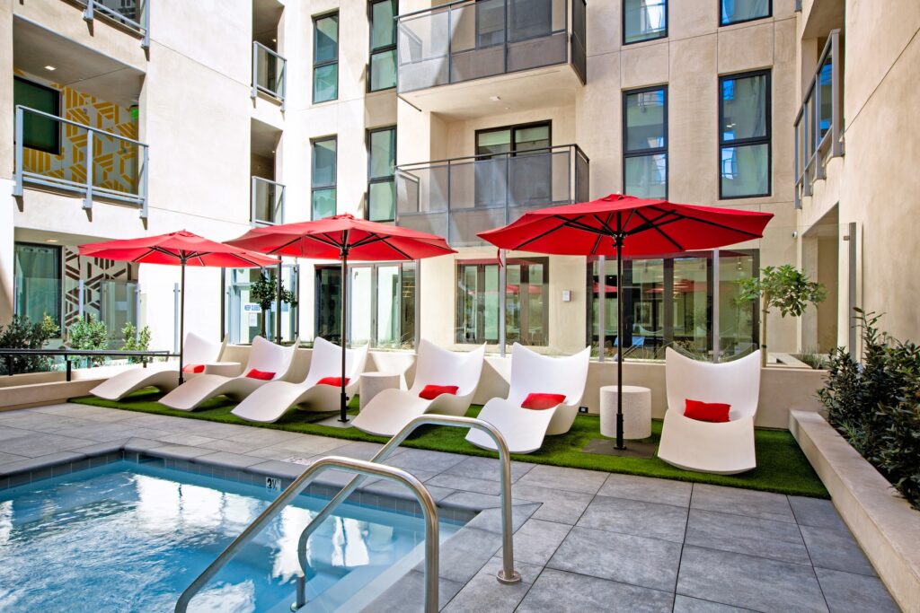 Outdoor courtyard with shaded seating, surrounding botanical gardens, and swimming pool