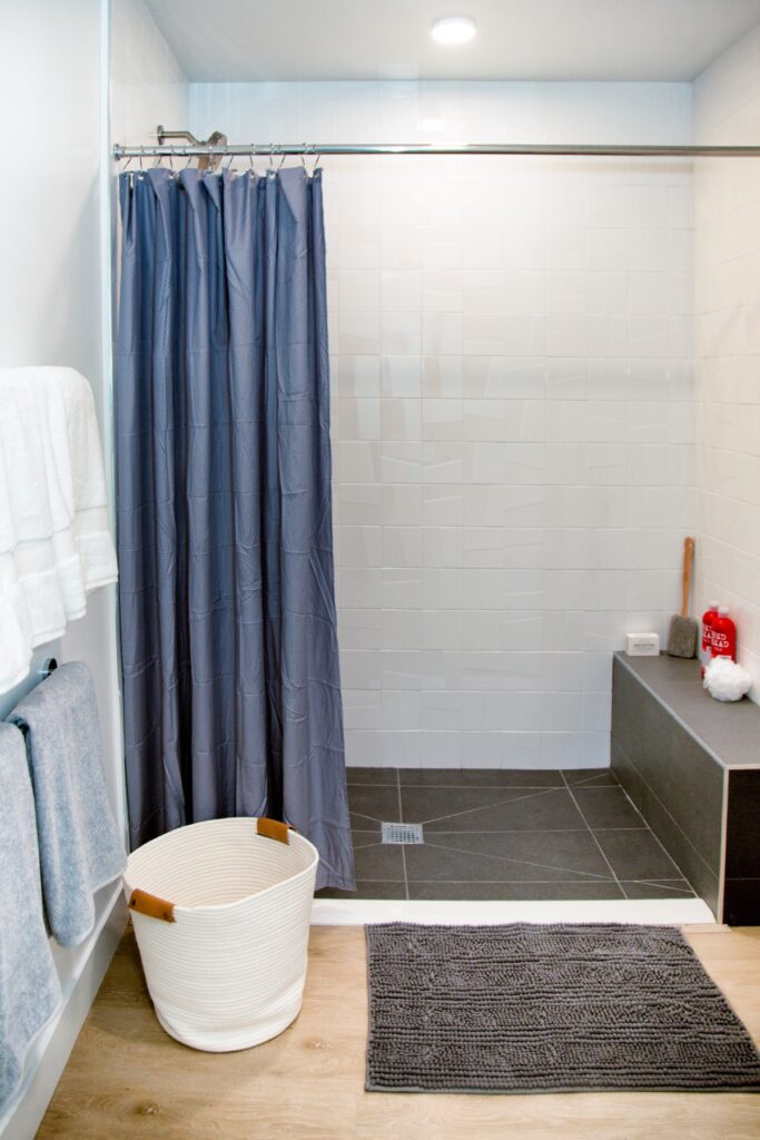 Bathroom area with stand up shower, towels, wood-style flooring, and designer lighting