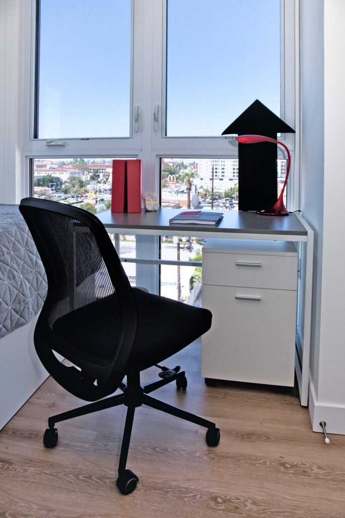 Bedroom area with office desk, floor-to-ceiling window, and wood-style flooring