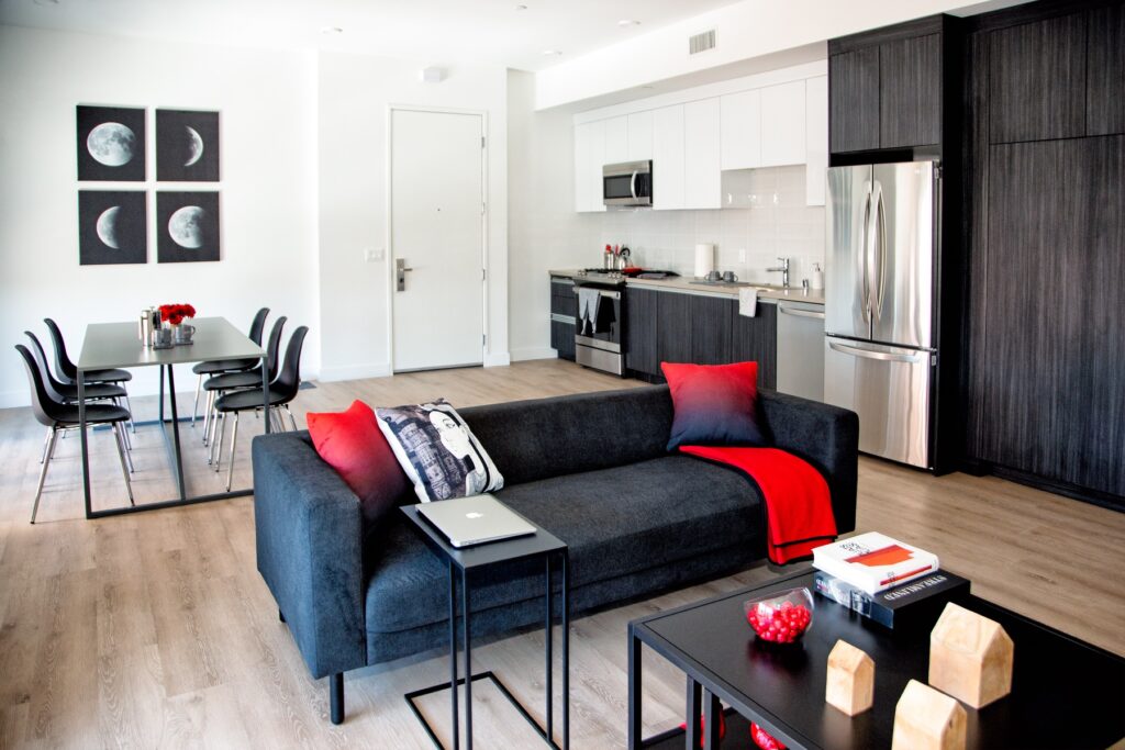 Living room and kitchen area with couch, dining table, stainless steel appliances, and wood-style flooring