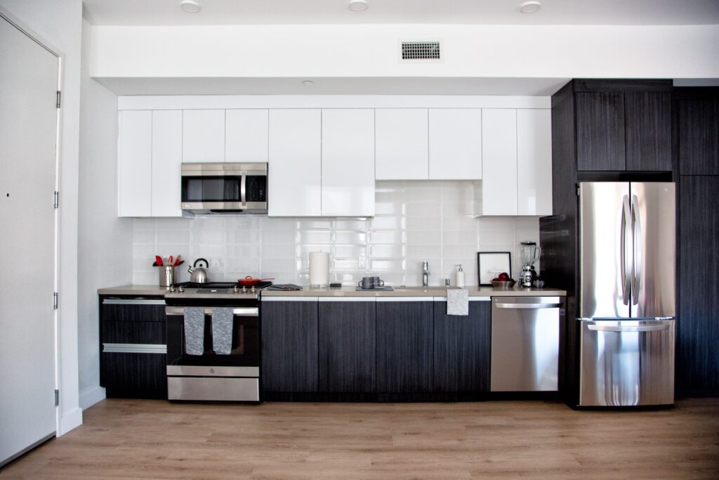 Kitchen area with oven, microwave, washer, refrigerator, and wood-style flooring