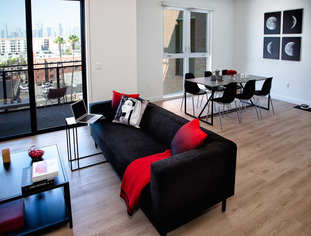 Living and dining room area with couch, dining table, floor-to-ceiling windows, and wood-style flooring
